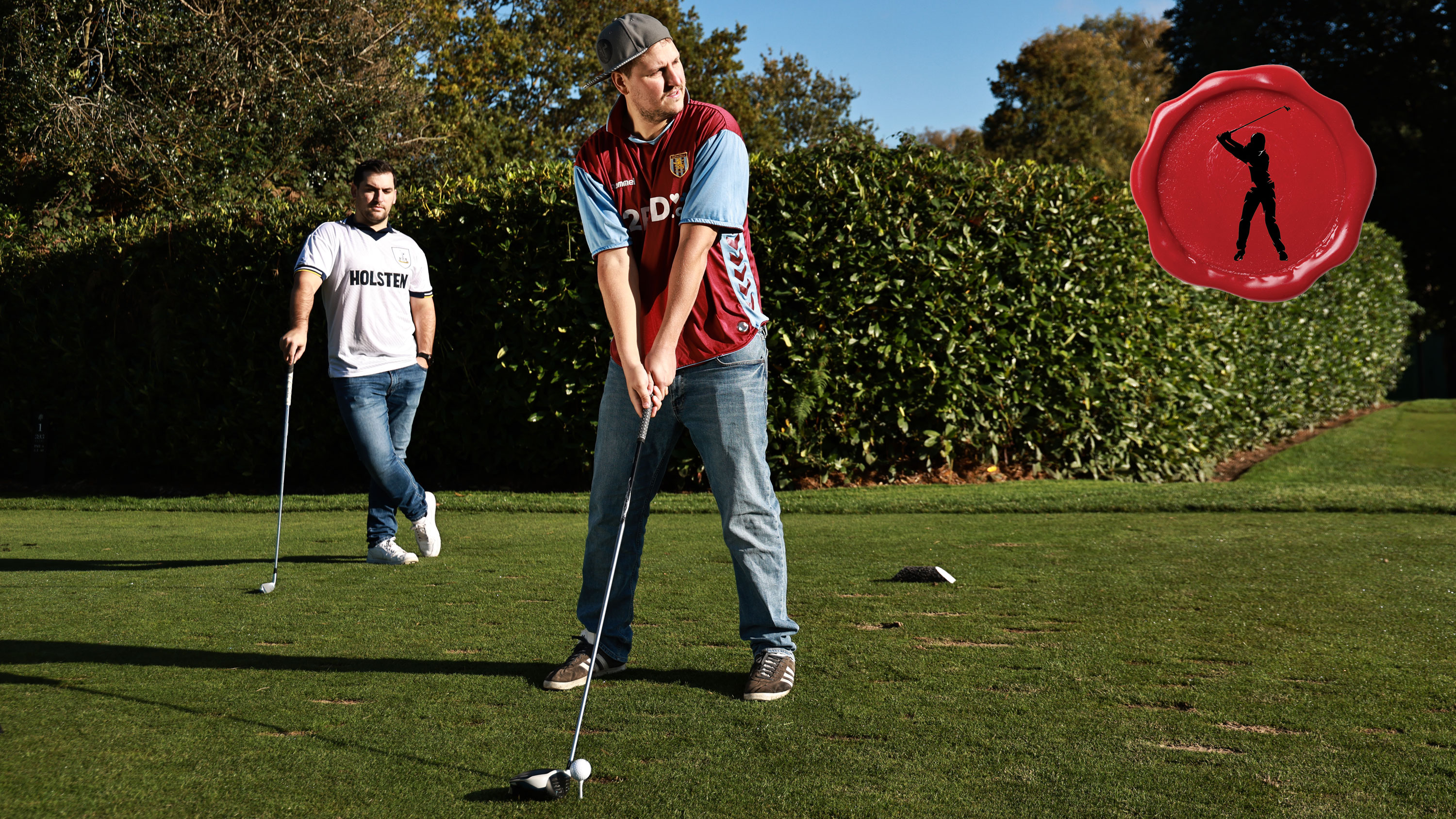 Two golfers teeing off wearing football shirts and jeans